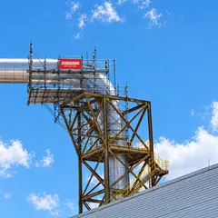 Andaime montado ao redor de uma tubulação industrial, com a placa da Andaime, sob céu azul